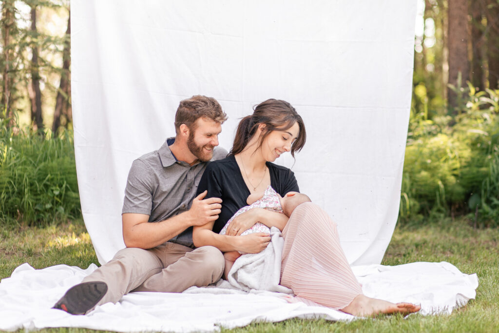 Family sitting on ground outside holding their new baby